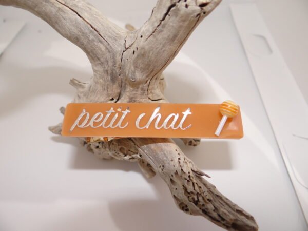 Barrette orange avec inscription "Petit chat" avec sucette