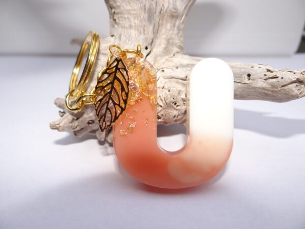 Porte clés lettre "U" rose et blanc avec plume dorée